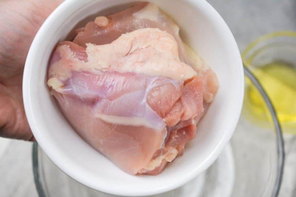 Adding boneless chicken thigh meat to bowl.