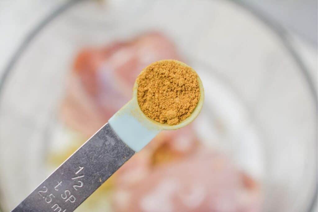 Adding cumin to the chicken in bowl.