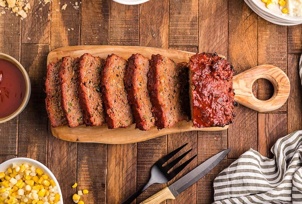 A smoked meatloaf cut into slices on a cutting board.