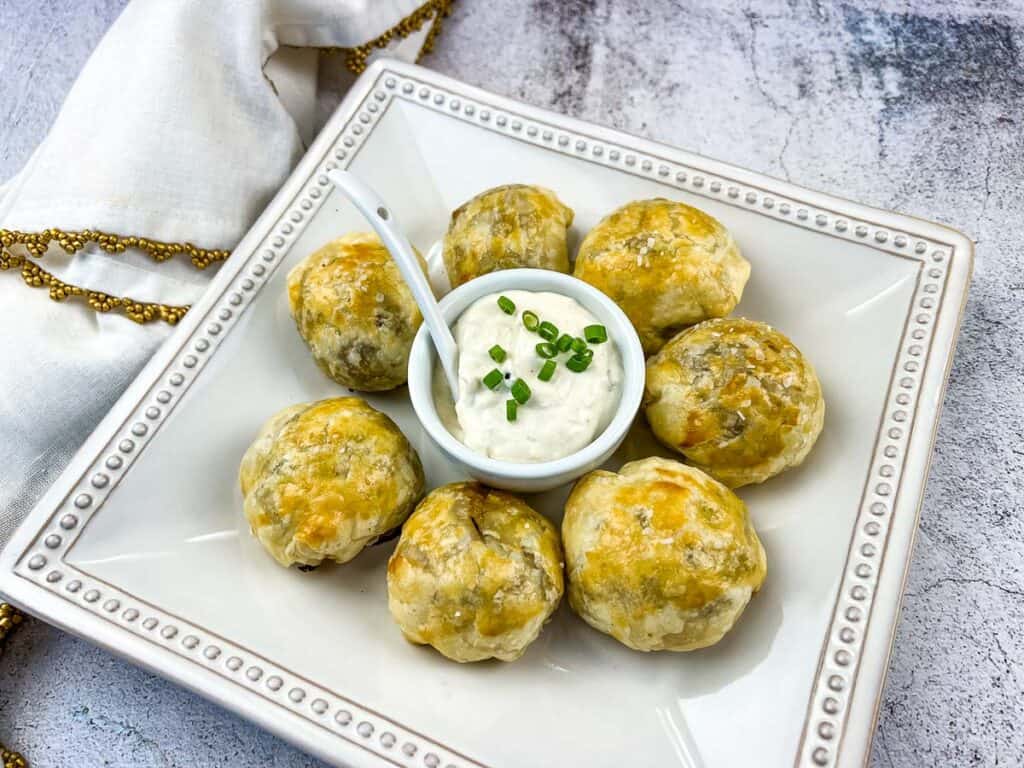 Beef Wellington Bites on  a white plate with sauce in the middle.