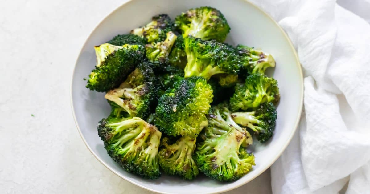 Easy Blackstone Broccoli Recipe in a white bowl with a spoon.