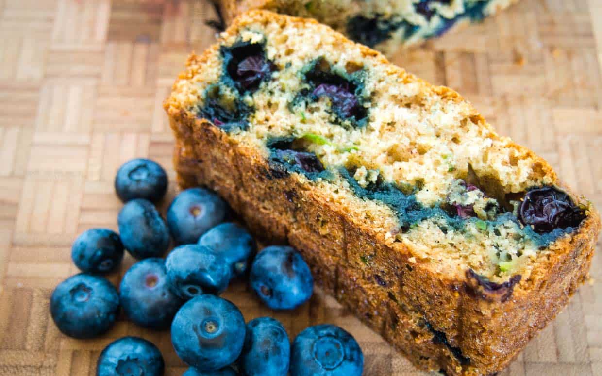 Loaf of zucchini bread sliced to show the blueberries inside.