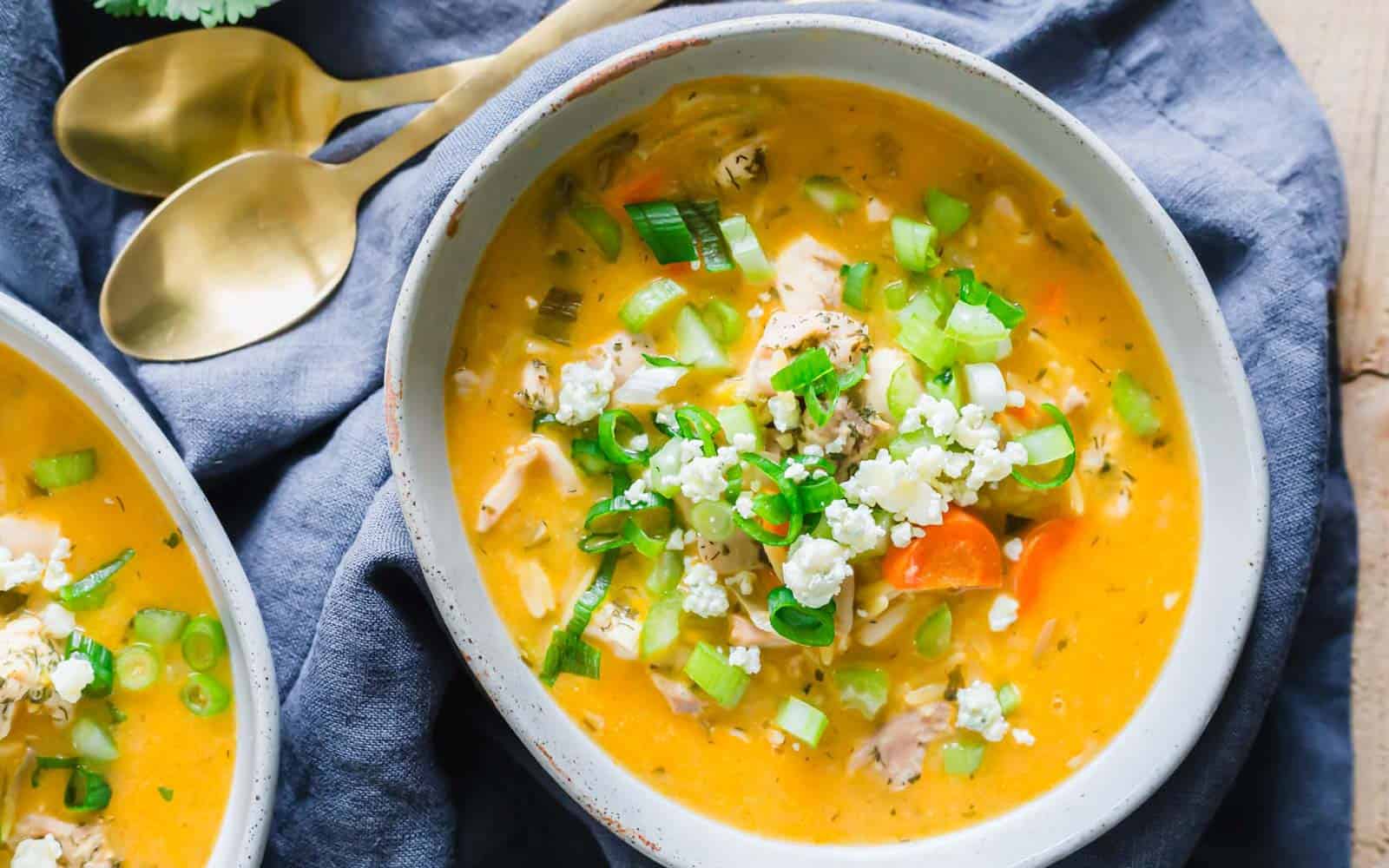 Buffalo chicken soup with orzo served in a bowl with blue cheese crumbles and green onion.