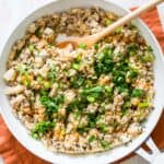 White skillet with buffalo ground turkey and cauliflower rice with a wooden spoon.