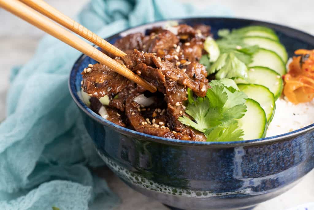 Bulgogi in a bowl with cucumber slices and cilantro.