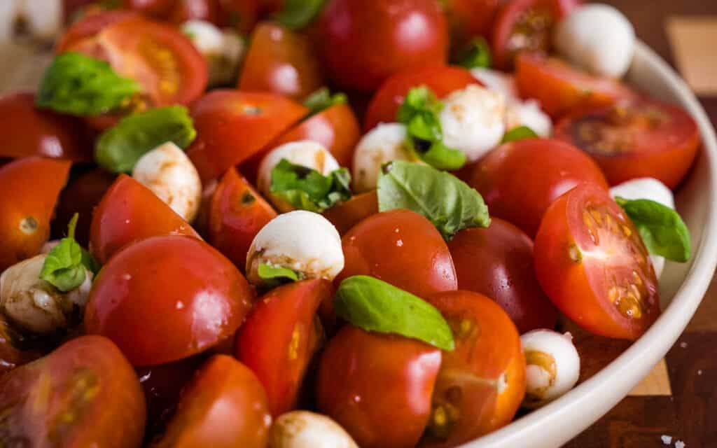 caprese salad with tomatoes and mozzarella cheese topped with basil.