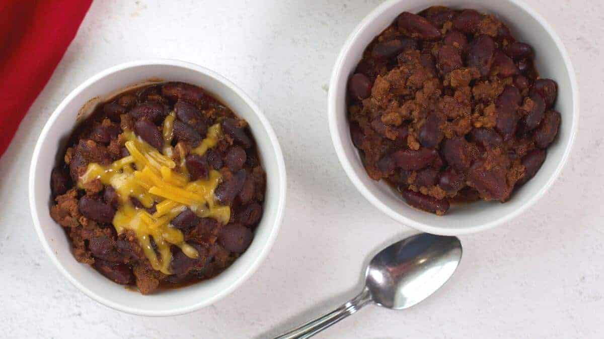 Crock Pot Chili served in two white bowls with spoon.