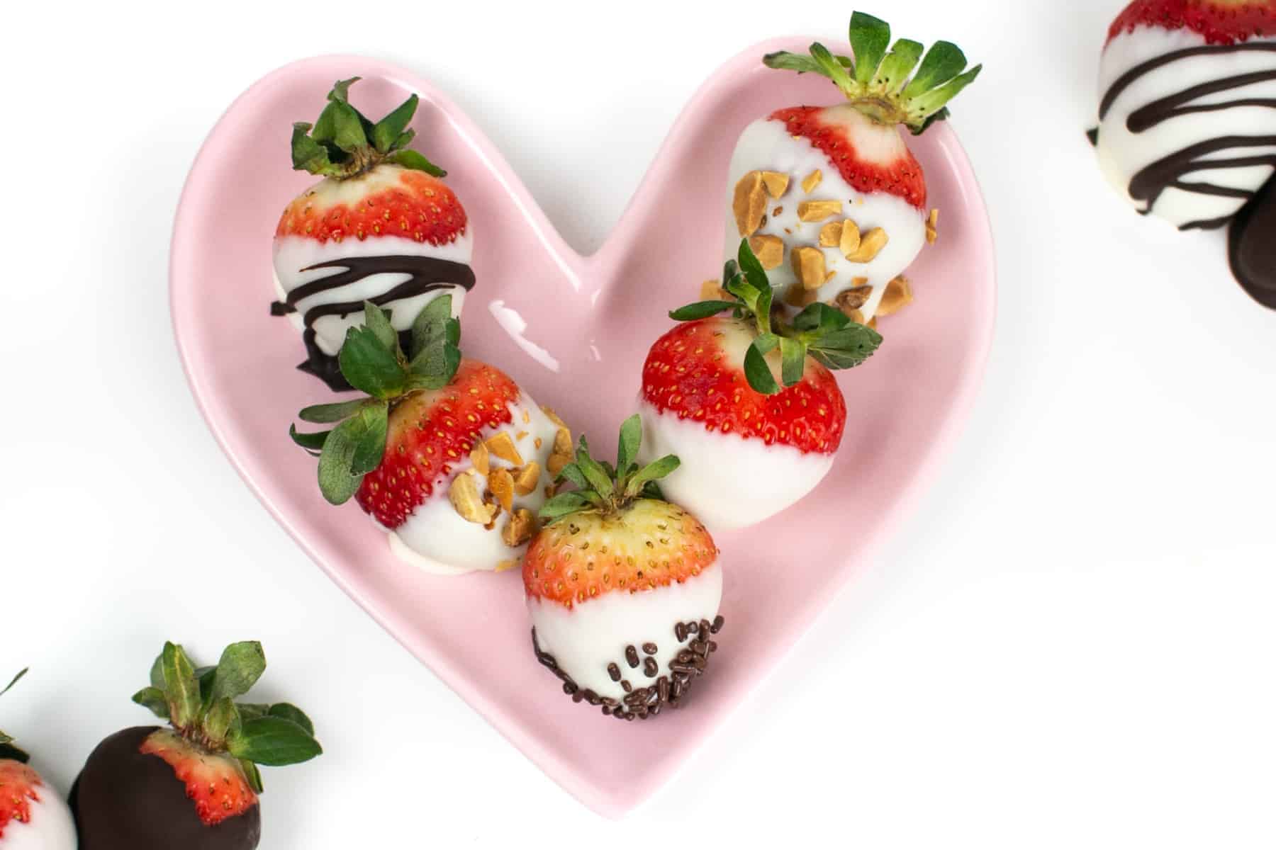 chocolate covered strawberries on a pink plate shaped like a heart.