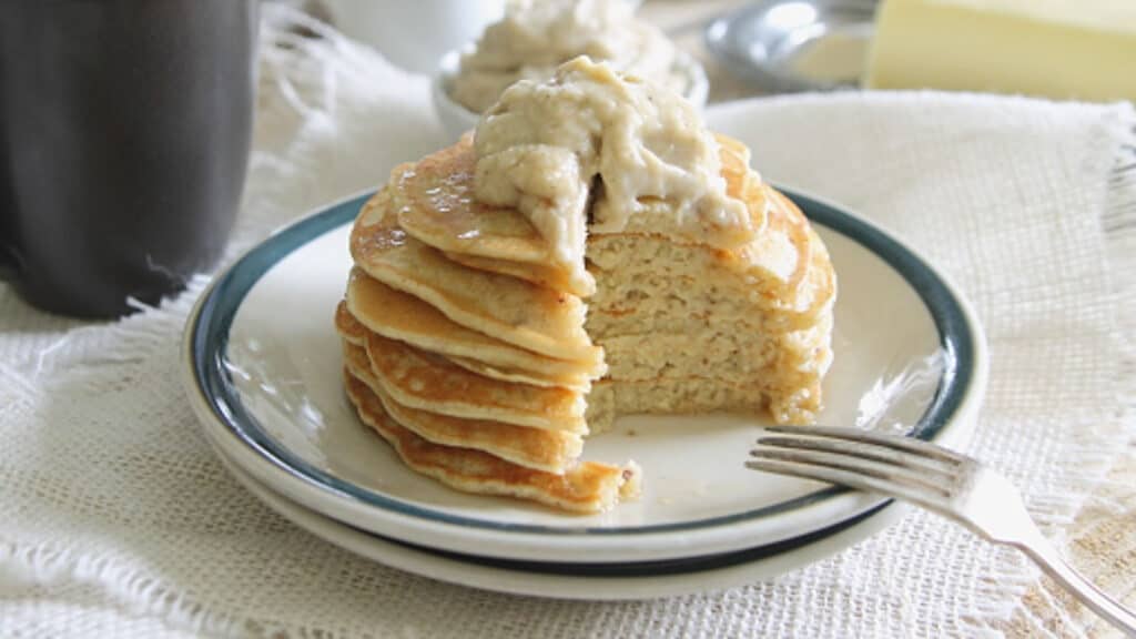 Coconut ricotta pancake stack on a plate with a creme fraiche topping.