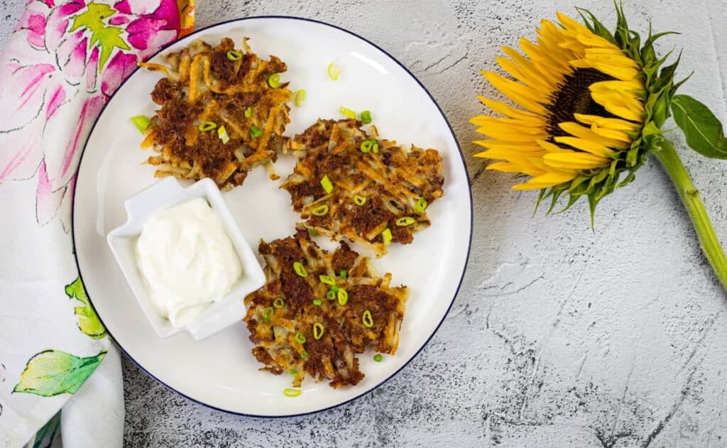 Corned beef fritters on a white plate with a sunflower.