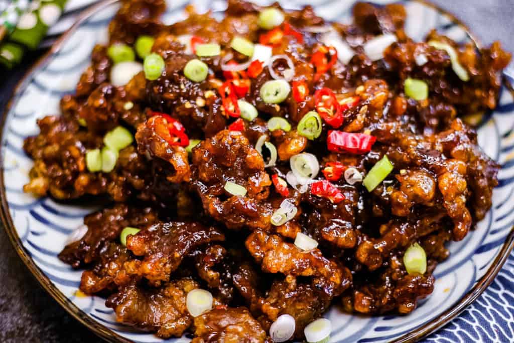 Low angle shot of crispy beef on a plate.
