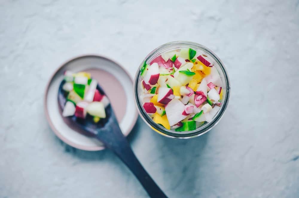 Fresh radish cucumber salsa in a glass container.