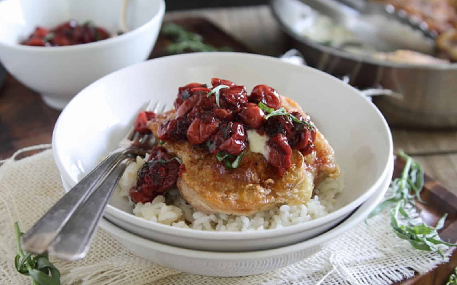 Fried chicken with goat cheese cherry sauce over white rice in a bowl.