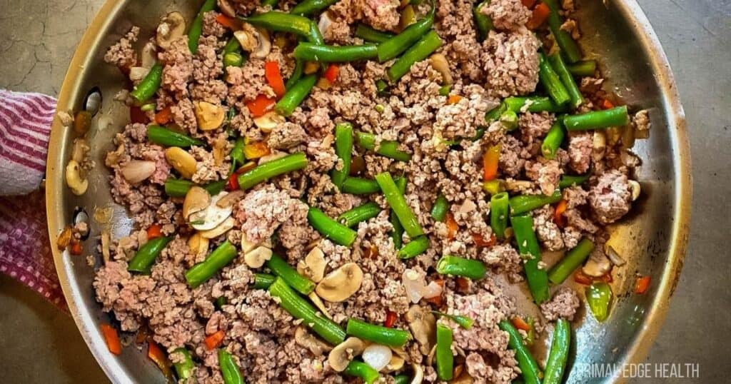 A picture of ground beef and green bean stir-fry in stainless steel skillet.