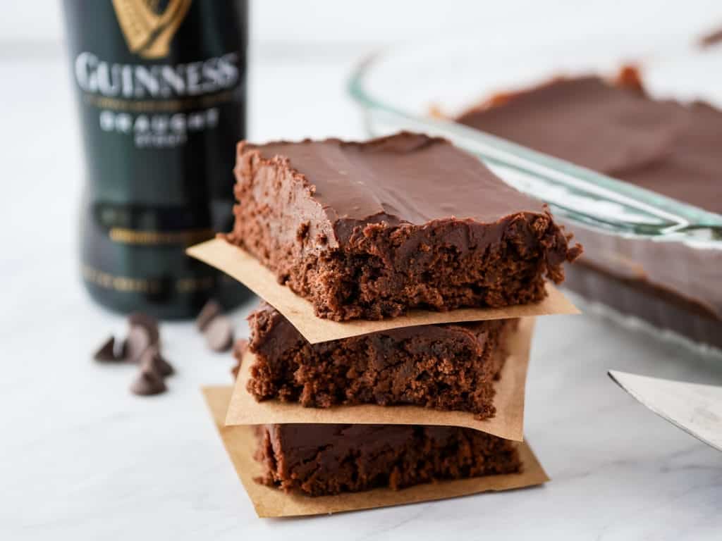 Guinness Brownies stacked in front of a bottle of beer.