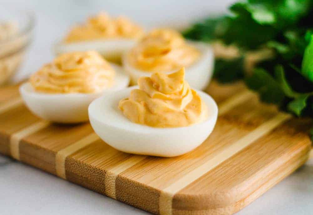 A batch of hummus deviled eggs on a serving board.