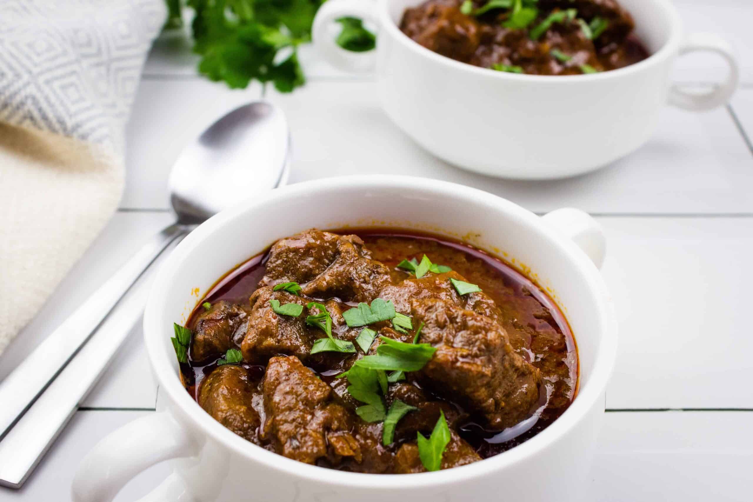 Two delectable bowls of beef stew showcasing a tantalizing blend of flavors, laid out invitingly on a rustic table.