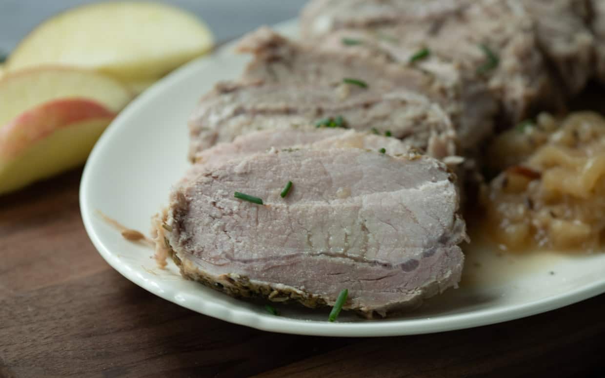 Instant Pot recipe for pork tenderloin served with apple sauce on a white plate.