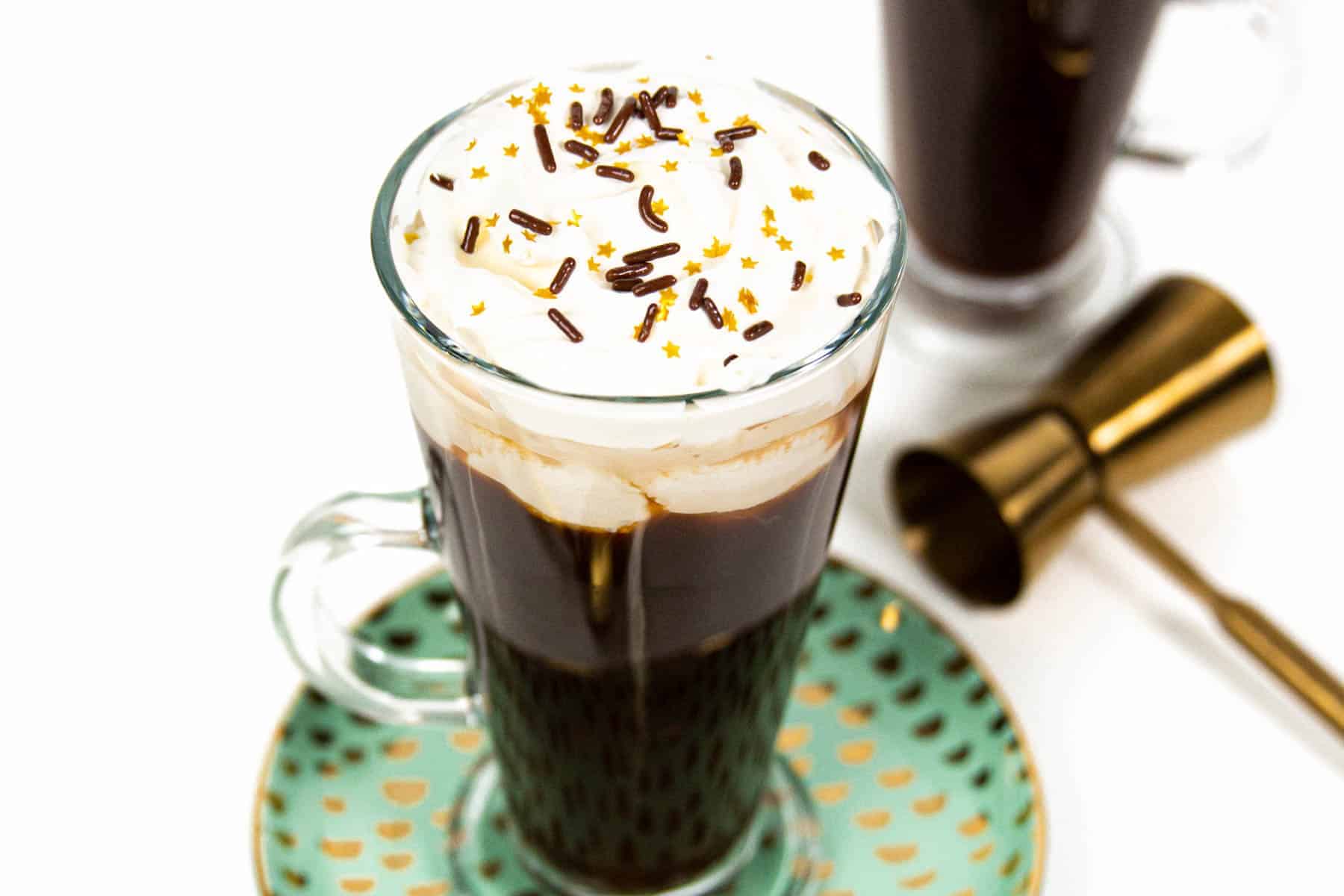 a glass mug with Irish coffee and whipped cream on top.