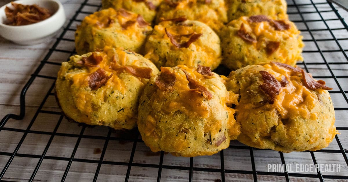 A picture of biscuits with bacon and cheese on top cooling on rack.