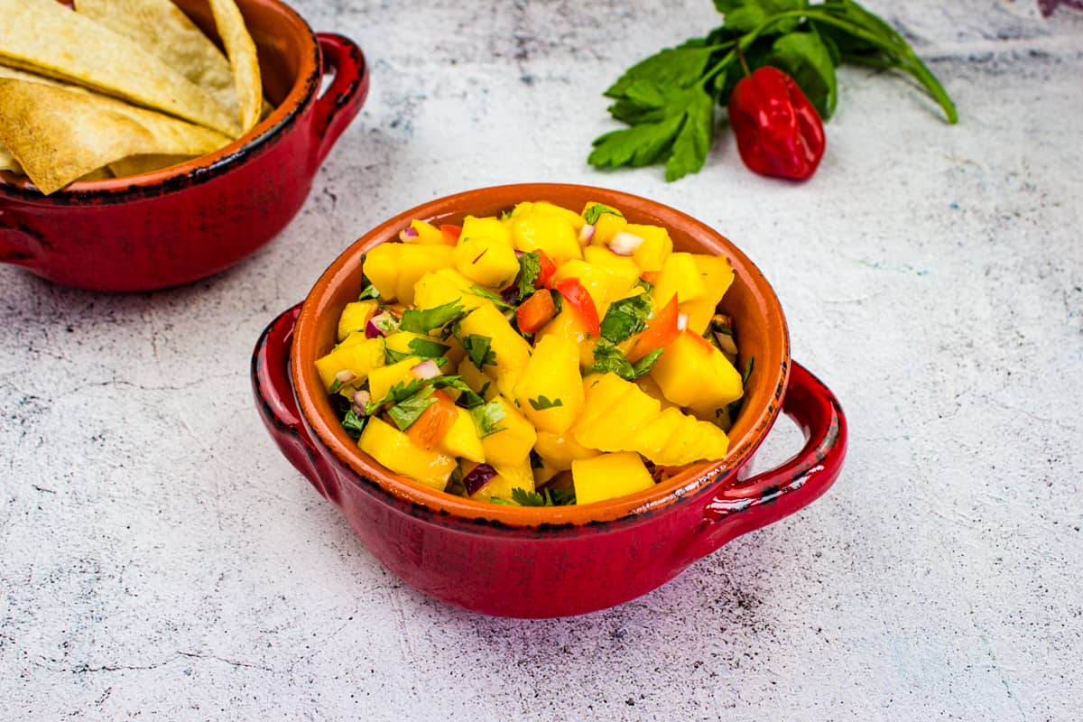 Mango Salsa in a bowl with chips nearby.