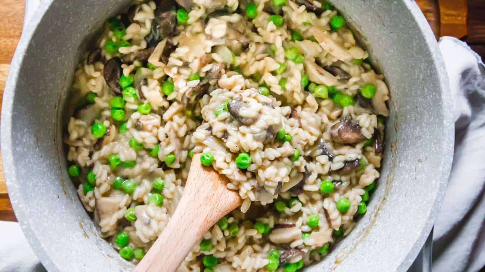 Mushroom risotto with peas and mushrooms in a pot with wooden spoon.