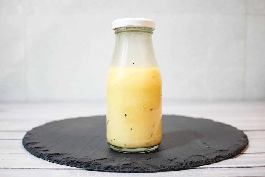 A clear glass jar filled with a yellow sauce.