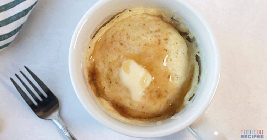 Pancake in a mug with butter and syrup.