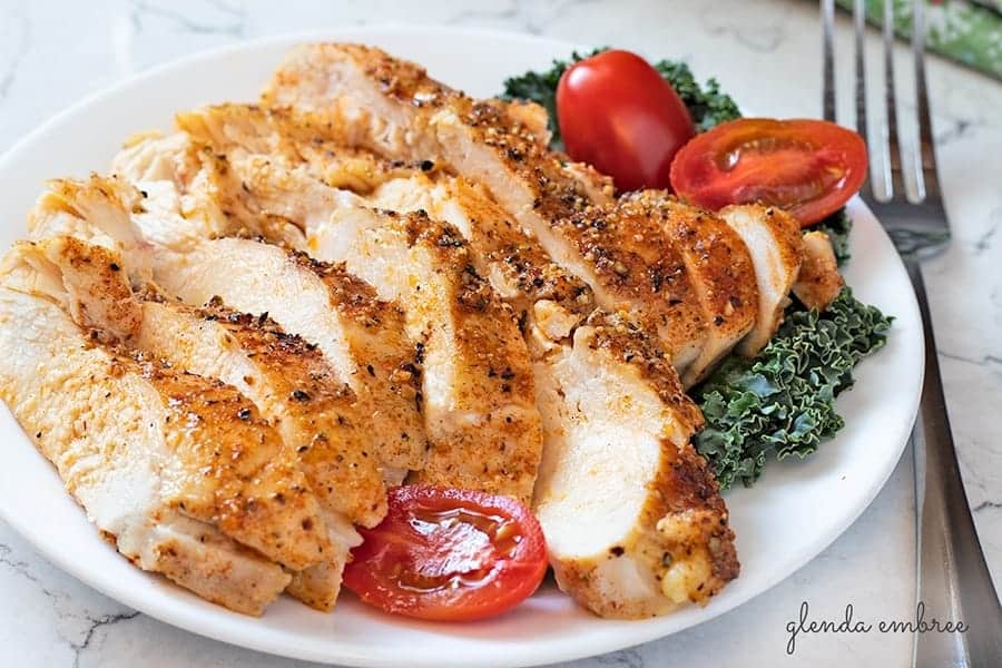 Perfectly Juicy Baked Chicken Breasts on plate with kale and tomato
