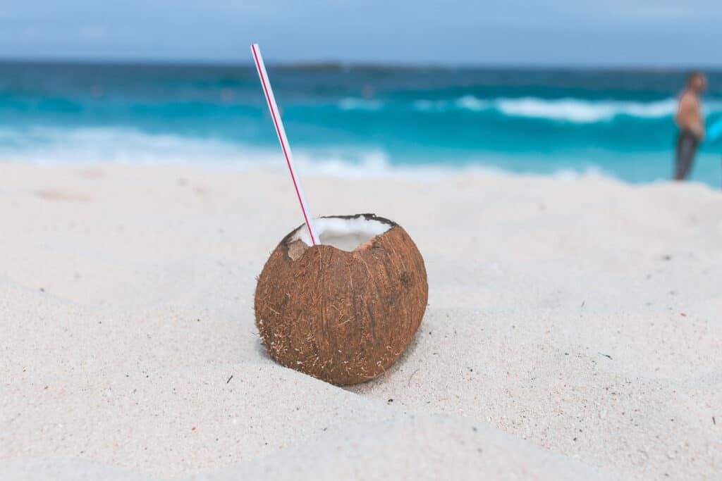 Whole coconut with opened top on the beach.