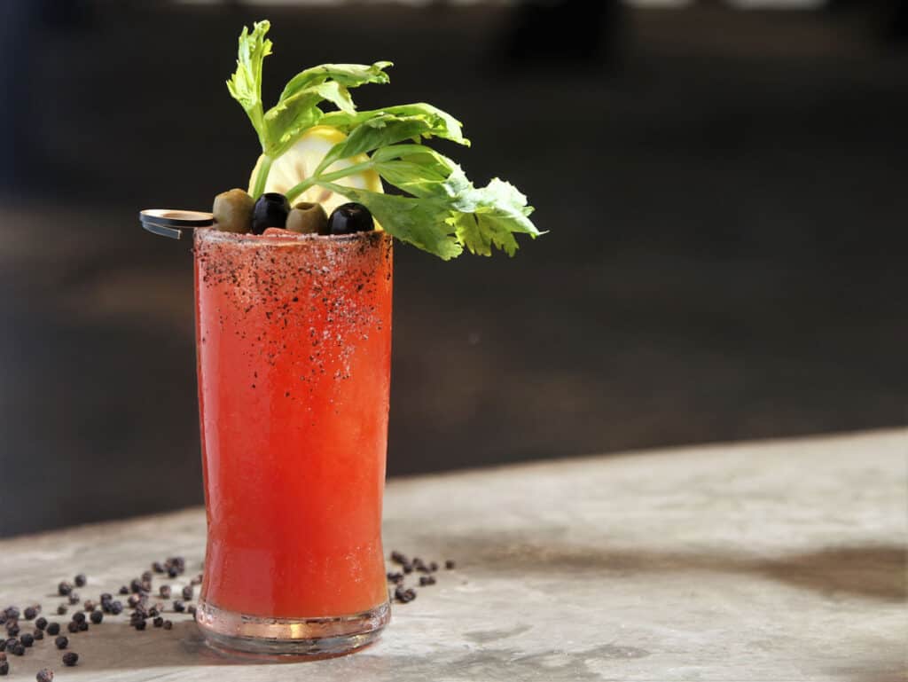 A bloody mary with a celery garnish sits on a countertop.