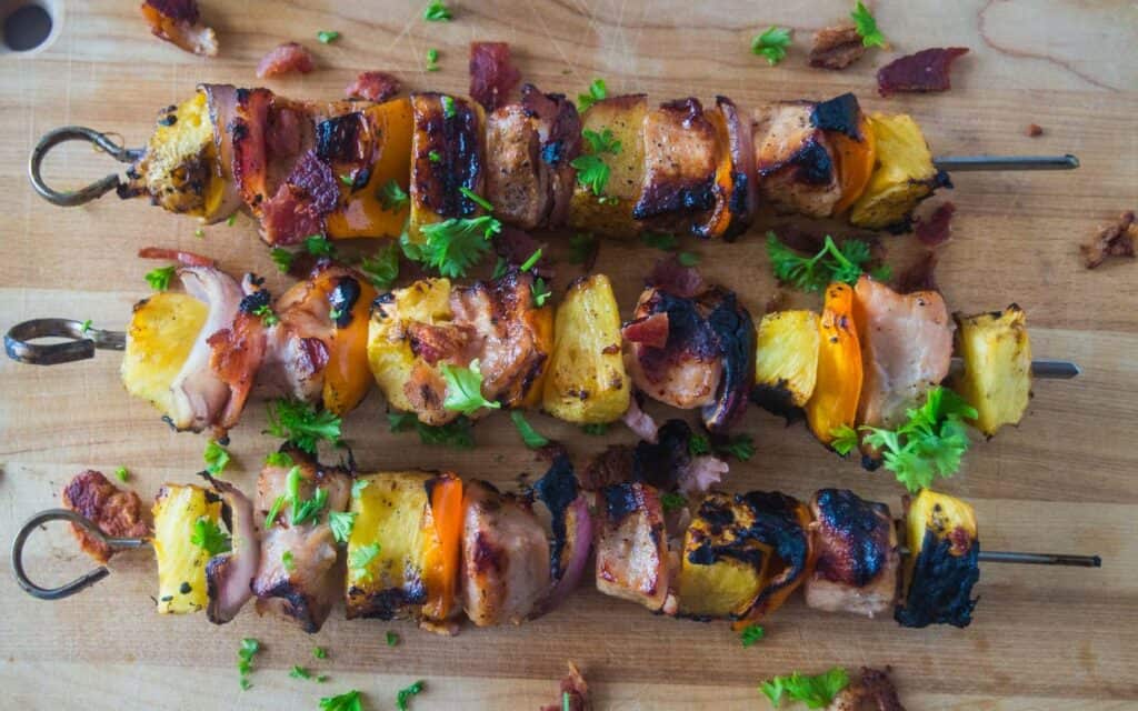 Pork Kabobs with pineapple and peppers on a wooden cutting board.