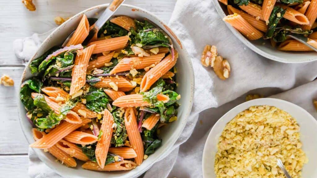 Red lentil pasta with garlic lemon greens in a bowl.