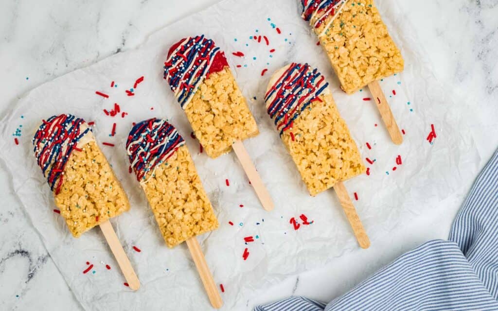 Rice krispie treats on a stick dipped in red, white and blue chocolate.