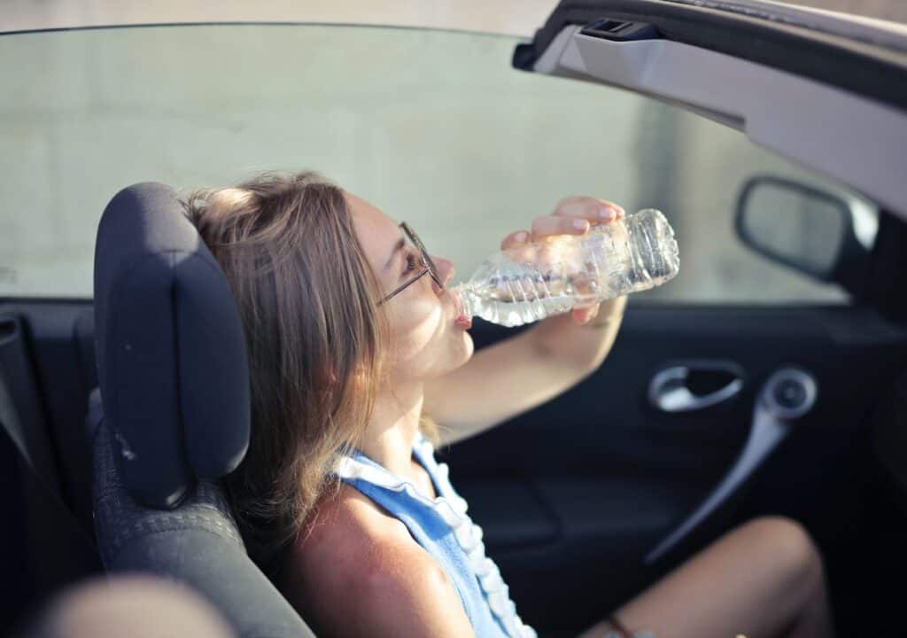Woman drinking from a water bottle while driving.