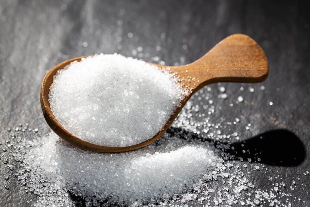 Sugar on a wooden spoon On a black background.