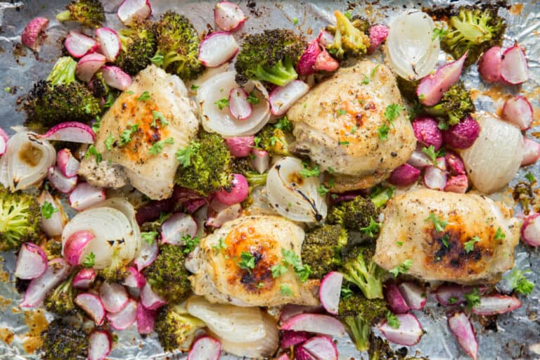 Chicken thighs with radishes and broccoli on a sheet pan.
