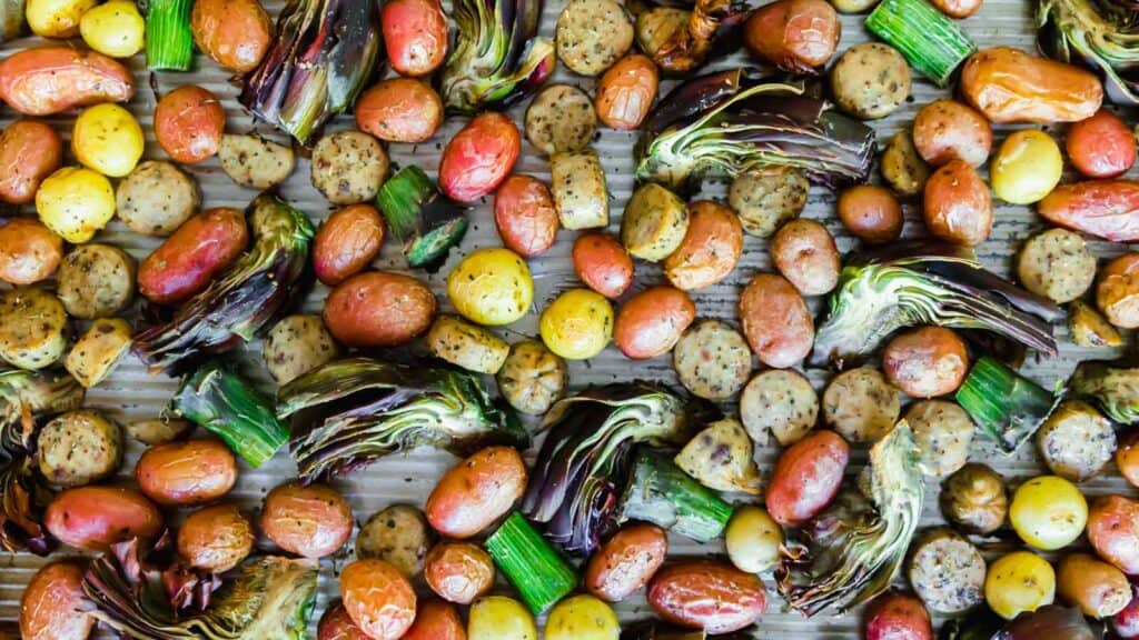 Chicken sausage and vegetables on a baking sheet.