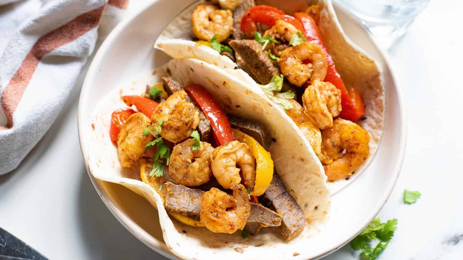 Shrimp and steak fajitas with peppers and onions.
