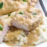 Slow Cooker Pork Chops on a plate covered with a creamy mushroom gravy and served on mashed potatoes.