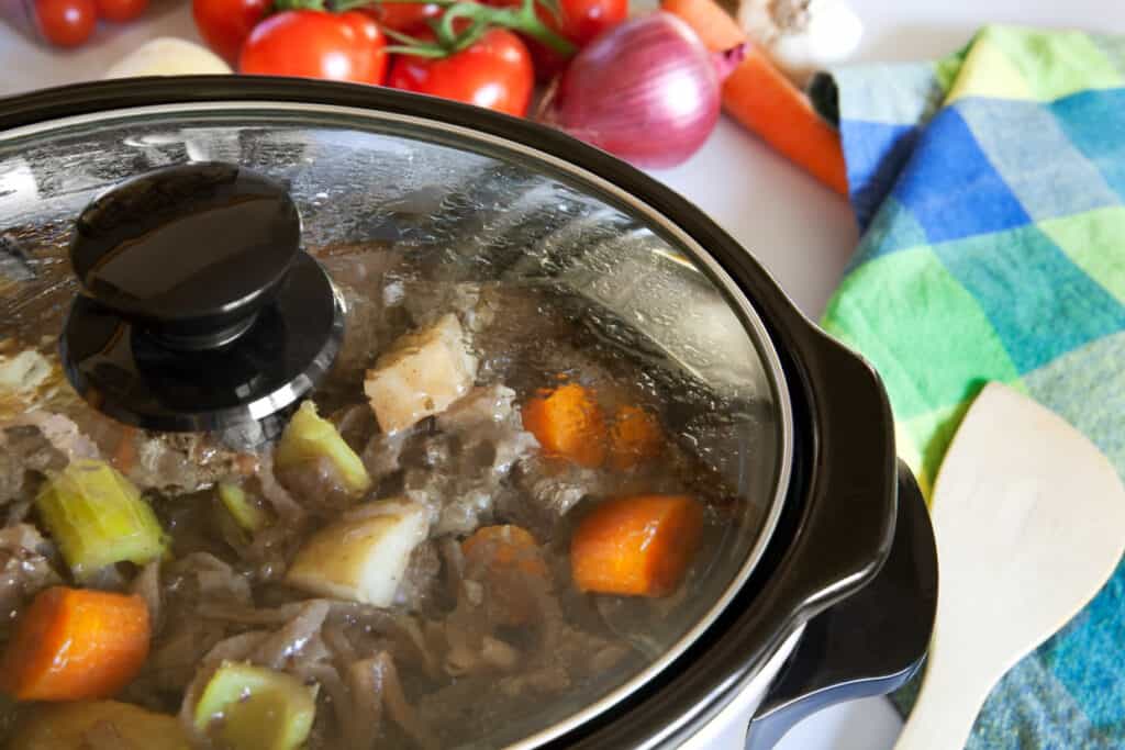 Stew in a slow cooker with a glass lid on top.