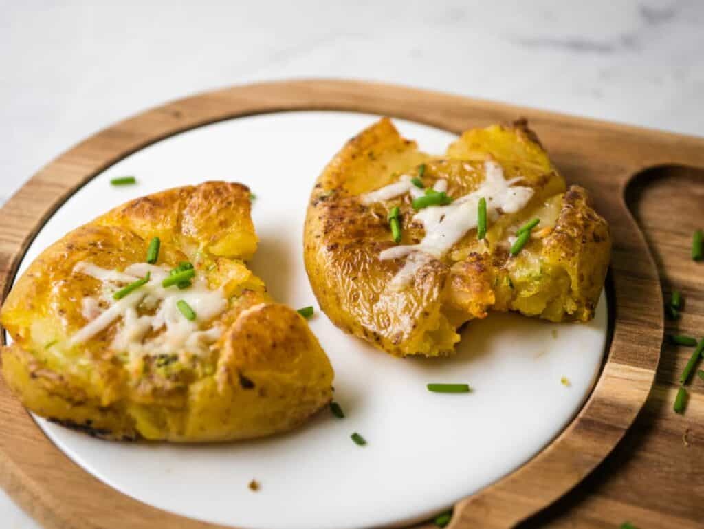 smashed potatoes on a white plate and cutting board.