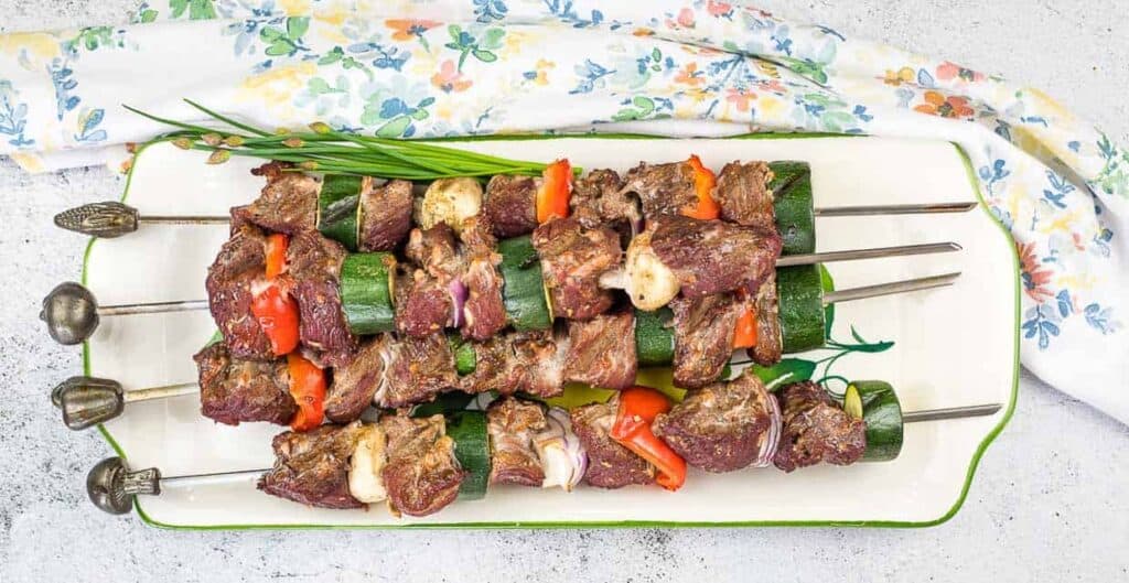 Smoked Beef Kabobs on a platter with zucchini.