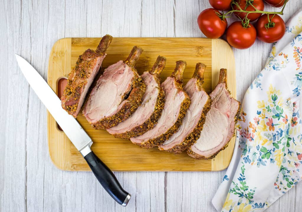 Sliced smoked pork rib roast on a cutting board.
