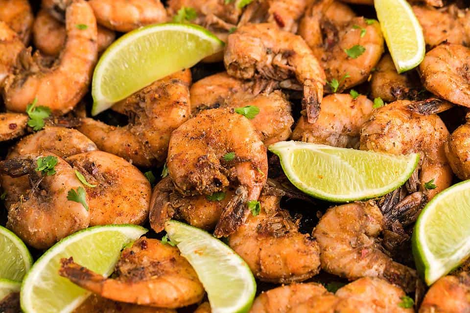 Smoked shrimp on a plate with lime wedges.