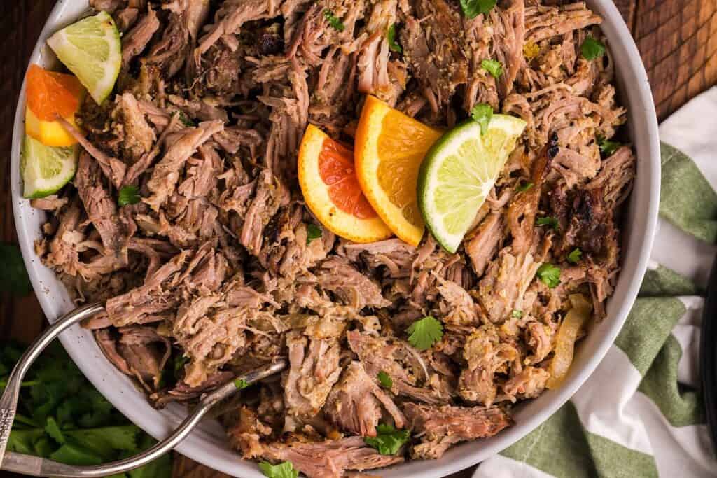 A bowl of smoked Cuban mojo pulled pork with citrus slices on top.