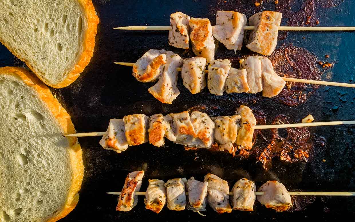 Spiedies cooking on a griddle with bread.