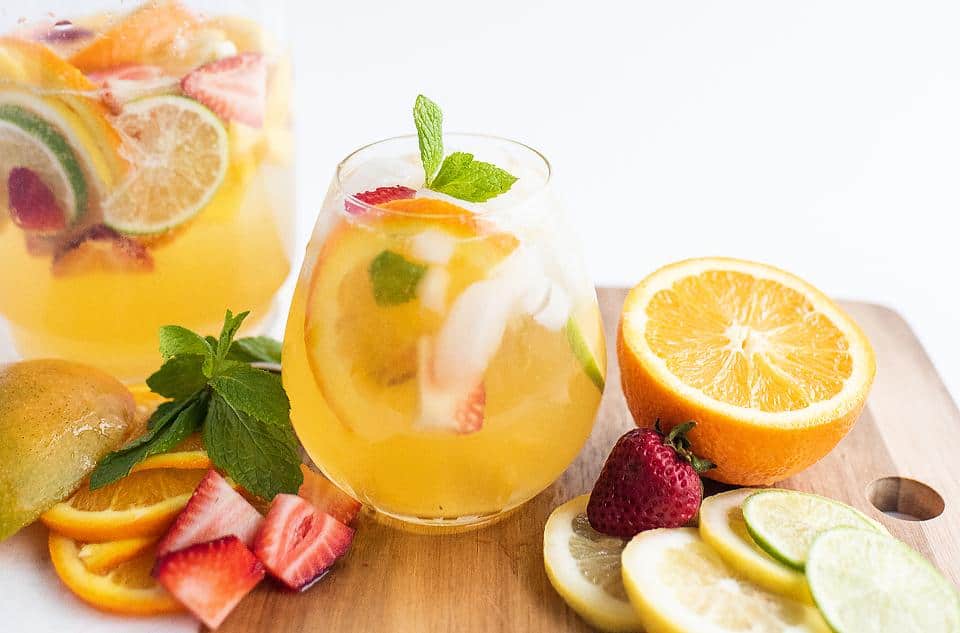 Mango White Sangria in glasses with fruit nearby.