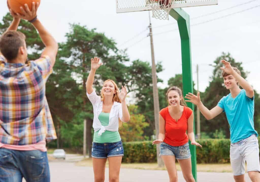 Teenagers playing basketball in a recreation park.
