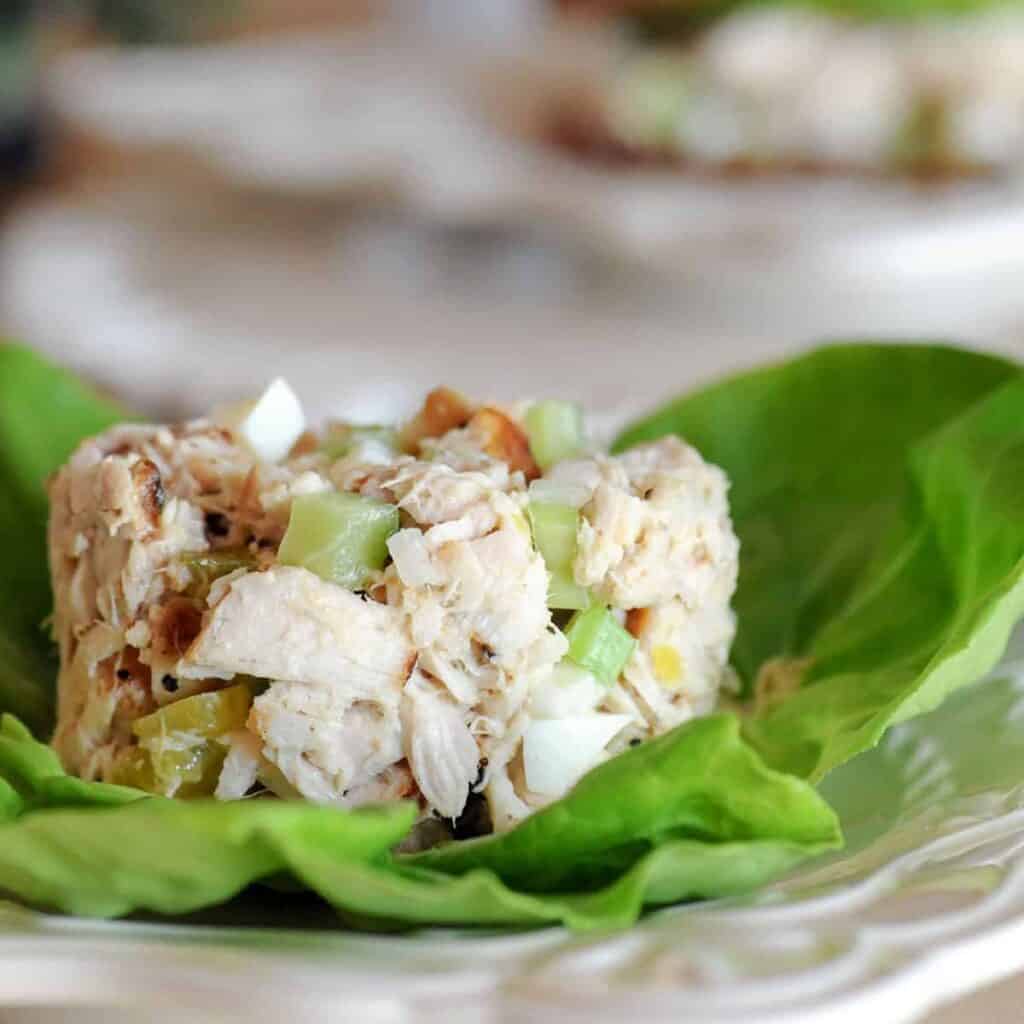 Tuna salad resting on a large green lettuce leaf.